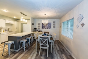 A modern kitchen with a central island, bar stools, and a dining table.