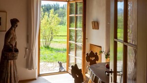 A rustic room with a wooden ceiling, a large window, and a statue. - Vacation apartment with large panoramic window (Teisendorf)