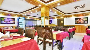 Ein Restaurant mit mehreren Tischen, Holzbalkendecke und modernem Interieur.