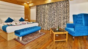 Ein Schlafzimmer mit einem Bett, einem blauen Sofa, einem Couchtisch und gemusterten Vorhängen.