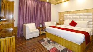 Ein Schlafzimmer mit einem hölzernen Kopfende, einem Bett mit weißer Bettwäsche und einem roten Kissen, einem weißen Sessel, einem Nachttisch aus Holz und einem violetten Vorhang.