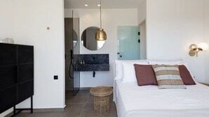 Une chambre à coucher moderne avec un lit, une armoire noire, un miroir, un miroir rond, un luminaire fixé au mur et un panier en osier.
