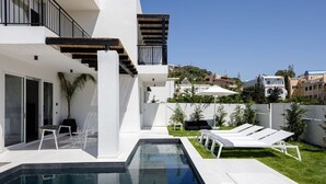 Une maison moderne dotée d’une piscine, d’un espace salon extérieur et offrant une vue sur le quartier environnant.