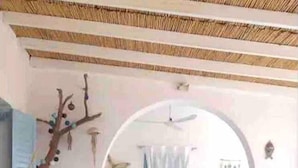 A room with a stone floor, a sofa, a tree wall art, and a blue curtain. - Villa 100 M From THE Beach 6 Room IN IOS Island (Ios)