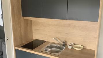 Een koelkast, kookgerei, borden en bestek, eettafels