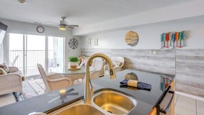 Eine moderne Küche mit Spüle aus Edelstahl, Deckenventilator und Essbereich mit Korbmöbeln.