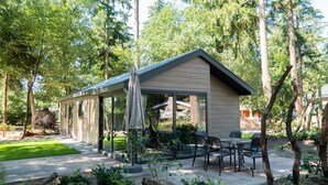 Una casa moderna con un porche cubierto, mobiliario exterior y un jardín.