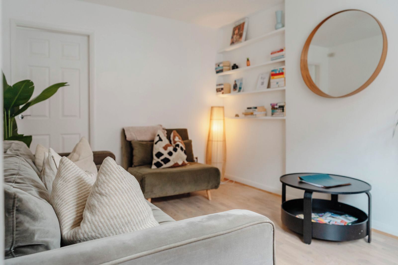Un salon avec un canapé, une table d’appoint, une lampe et une bibliothèque.