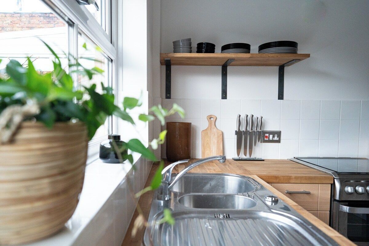 Une cuisine équipée d’un évier, d’une cuisinière et d’étagères où sont rangés la vaisselle.