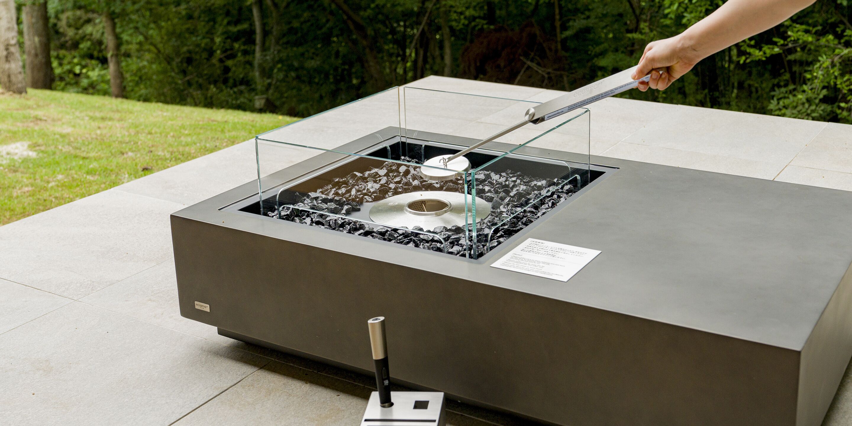 Un élément décoratif aquatique extérieur moderne, doté d’un bassin métallique et d’une structure en verre.