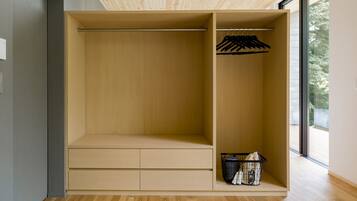 Un armario moderno con detalles de madera, una barra para colgar y una cesta con bolsos.