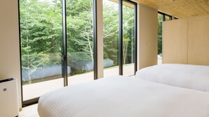 A bedroom with a large bed, a wooden ceiling, and a view of trees through large windows. - Rakuten STAY VILLA Aso Kurokawa (Minamioguni)