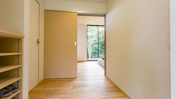 A hallway with wooden flooring, a sliding door, and a view of trees through a window.