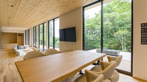 A modern conference room with a long table, comfortable seating, large windows, and a view of greenery. - Rakuten STAY VILLA Aso Kurokawa (Minamioguni)