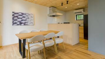 A modern kitchen with a wooden table and chairs, a white island, and a large window.