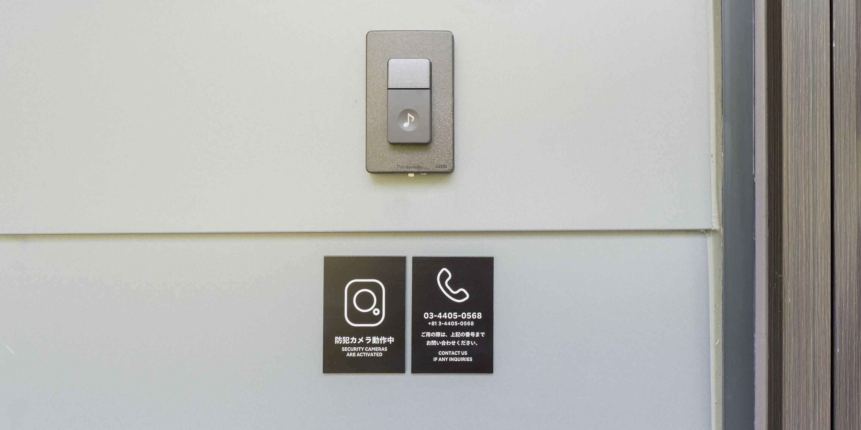 A security camera and contact information on a wall.