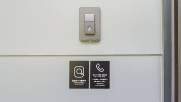 A security camera and contact information on a wall.