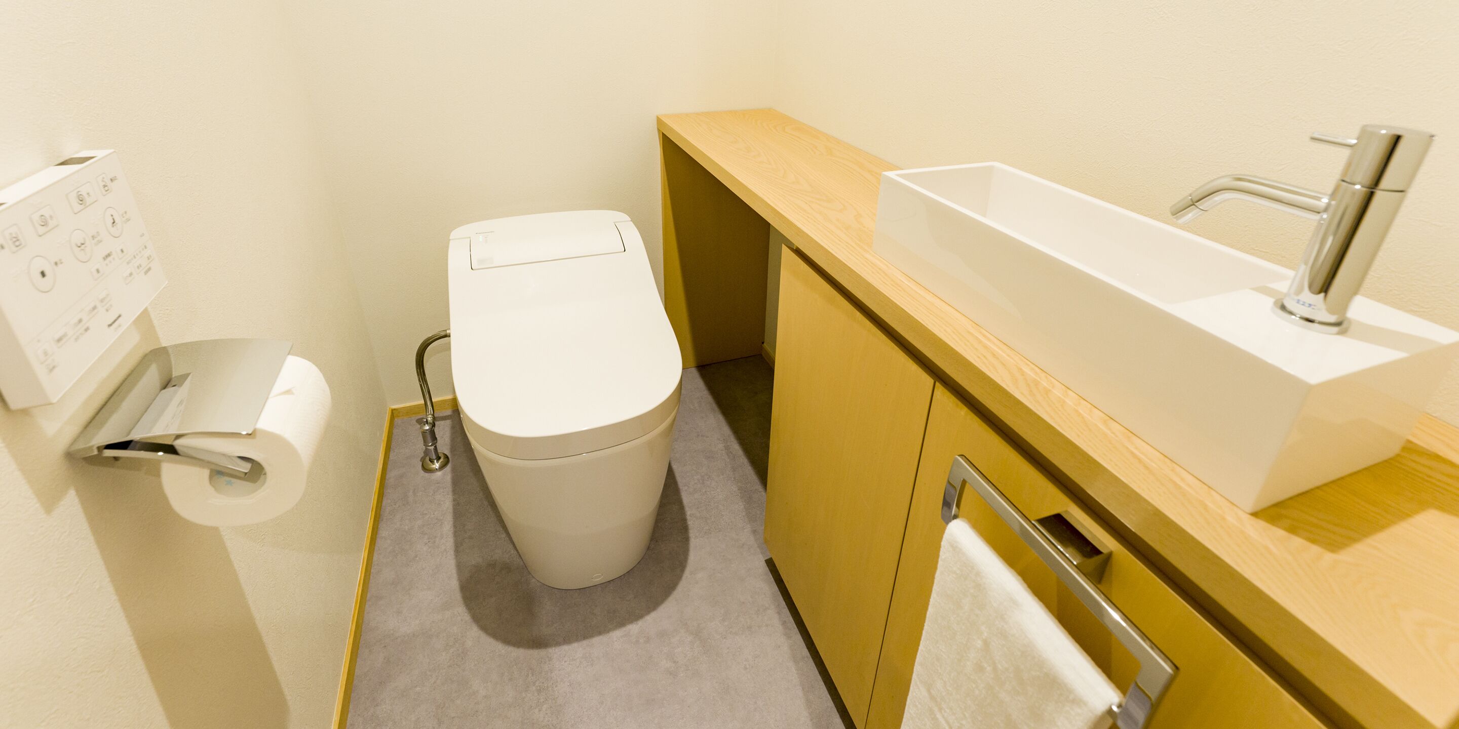 Een moderne badkamer met toilet, wastafel en handdoekhouder.