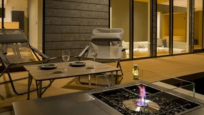 A modern outdoor dining area with two chairs, a table, and a built-in fire feature. - Rakuten STAY VILLA Aso Kurokawa (Minamioguni)