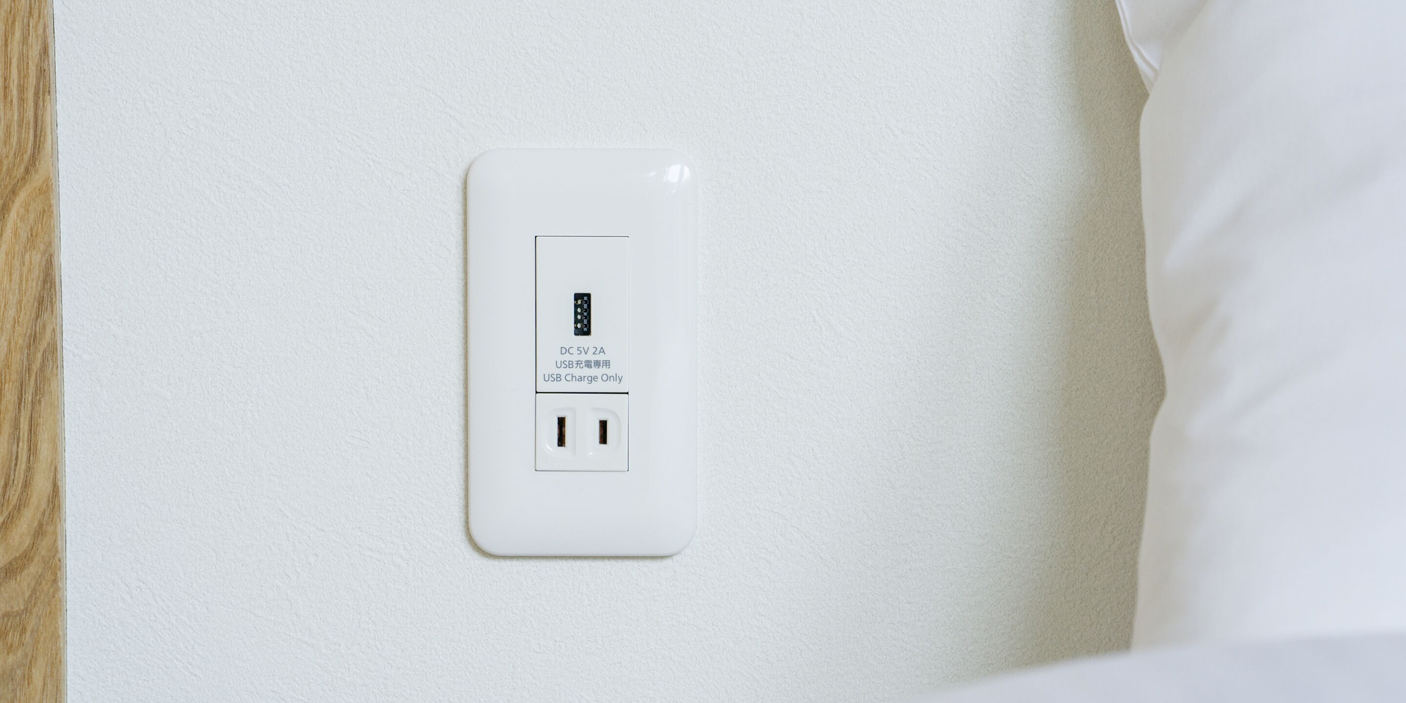 A white electrical outlet with a USB charging port on a textured wall.