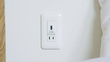 A white electrical outlet with a USB charging port on a textured wall.