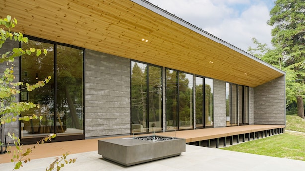 A modern building with large windows, a wooden ceiling, and a concrete bench area. - Rakuten STAY VILLA Aso Kurokawa (Minamioguni)