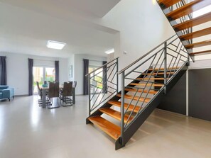 Een modern interieur met een trap, een eethoek en uitzicht door een glazen deur.