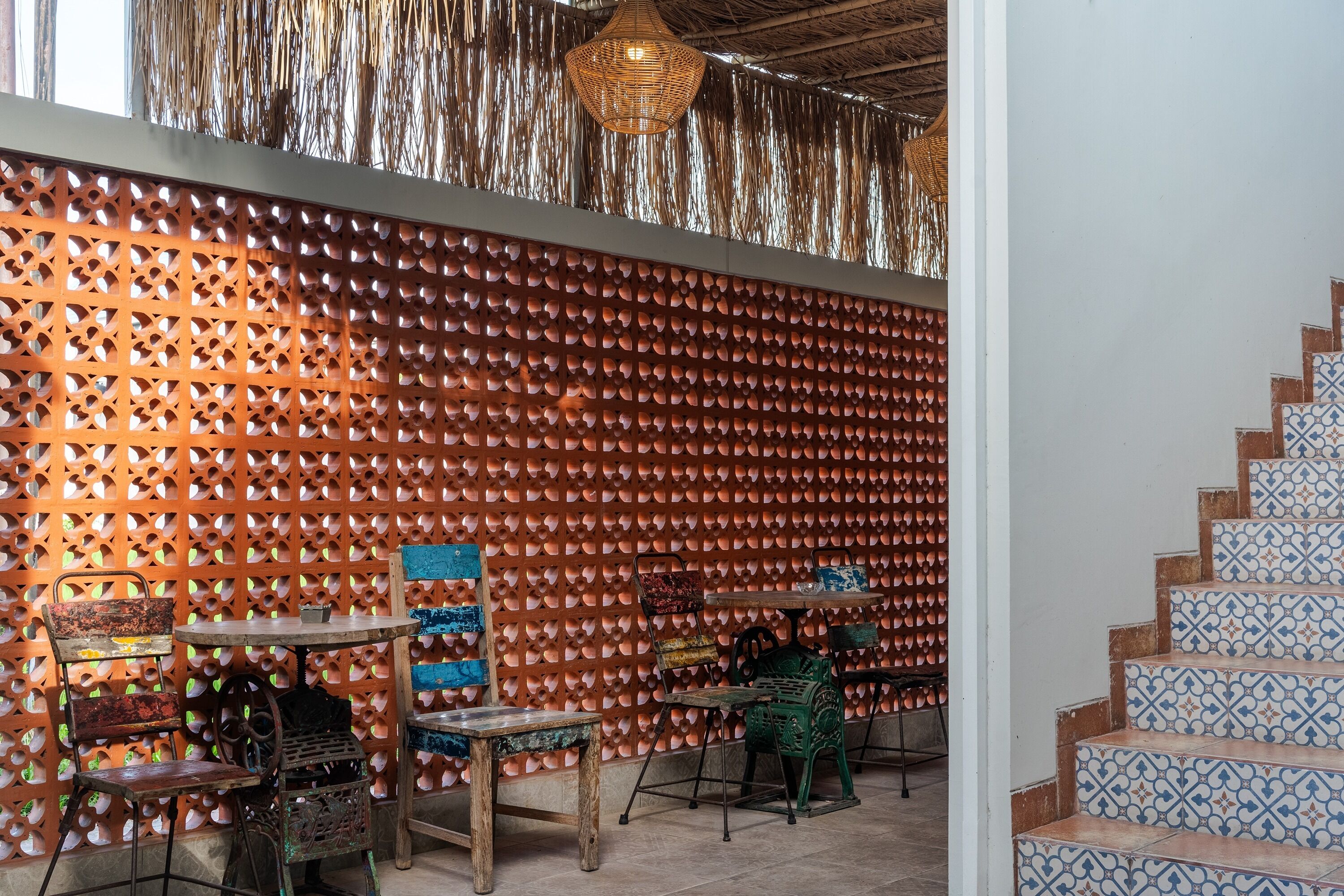 Un espace intérieur chaleureux, avec un mur décoré de motifs, un escalier aux carreaux décorés et des meubles rustiques.