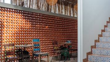 Un espace intérieur chaleureux, avec un mur décoré de motifs, un escalier aux carreaux décorés et des meubles rustiques.