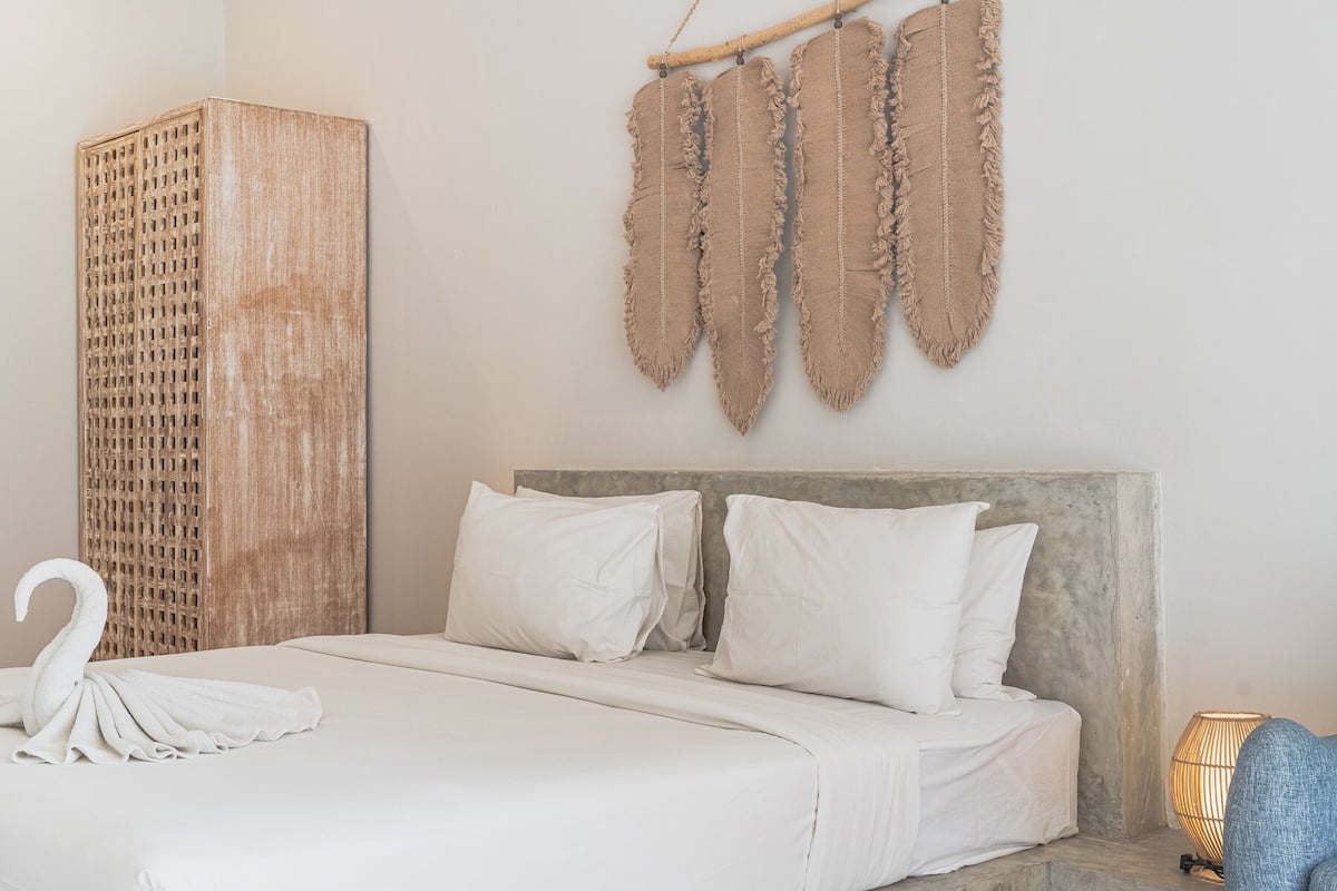 A bed with white linens, a headboard, and a wall-mounted decorative piece.