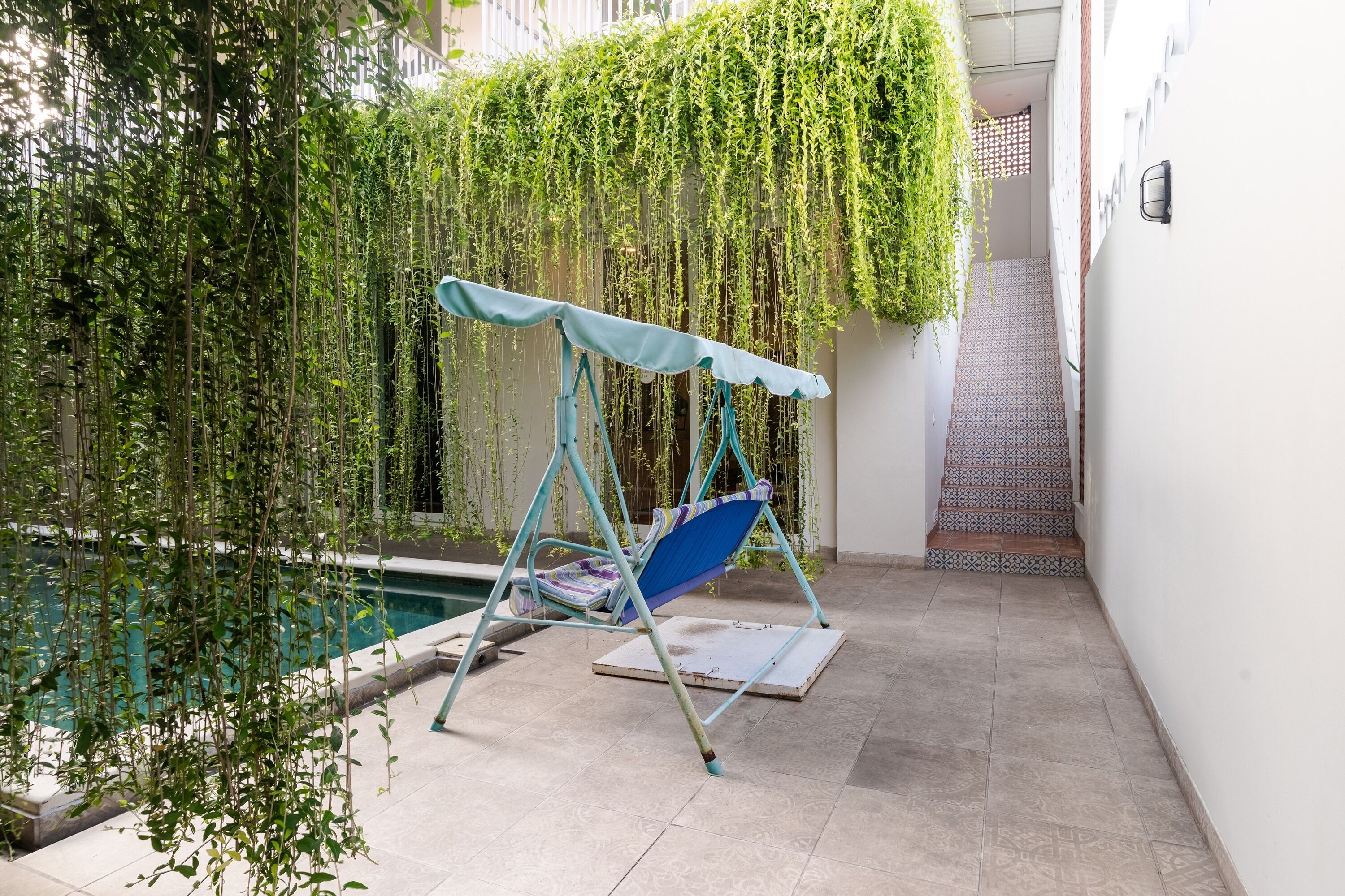 A patio area with a swing chair, a small pool, and a staircase leading to an upper level.