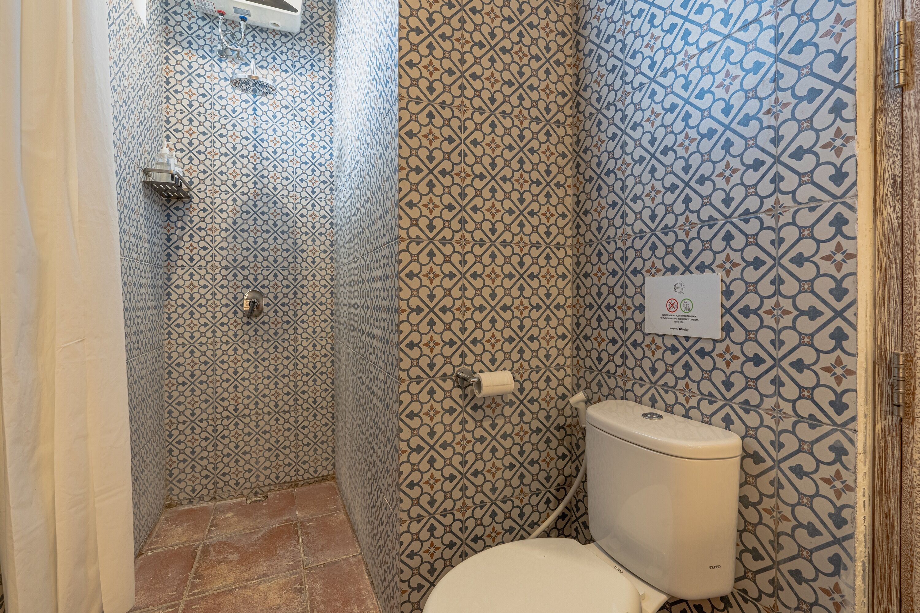 A bathroom with patterned tiles, a toilet, and a shower area.