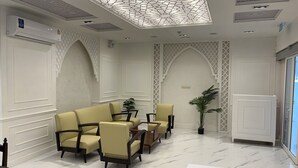 A room with a high ceiling, patterned ceiling design, and a seating area with sofas and chairs. - Anwari Hotel (Bangkok)