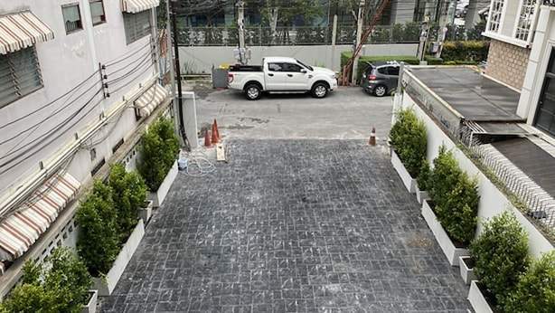 A parking area with a white pickup truck, surrounded by buildings with balconies and power lines. - Anwari Hotel (Bangkok)