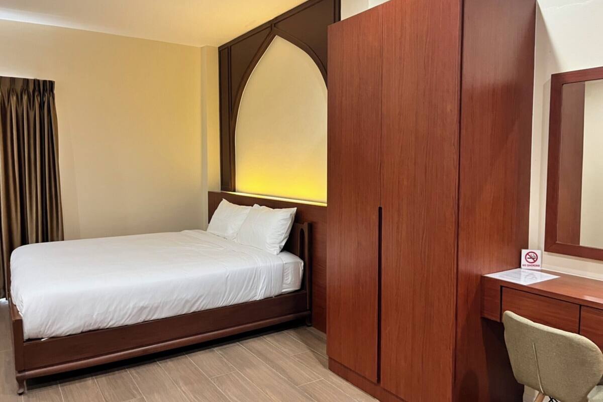 A hotel room with a bed, a desk, and a wardrobe.