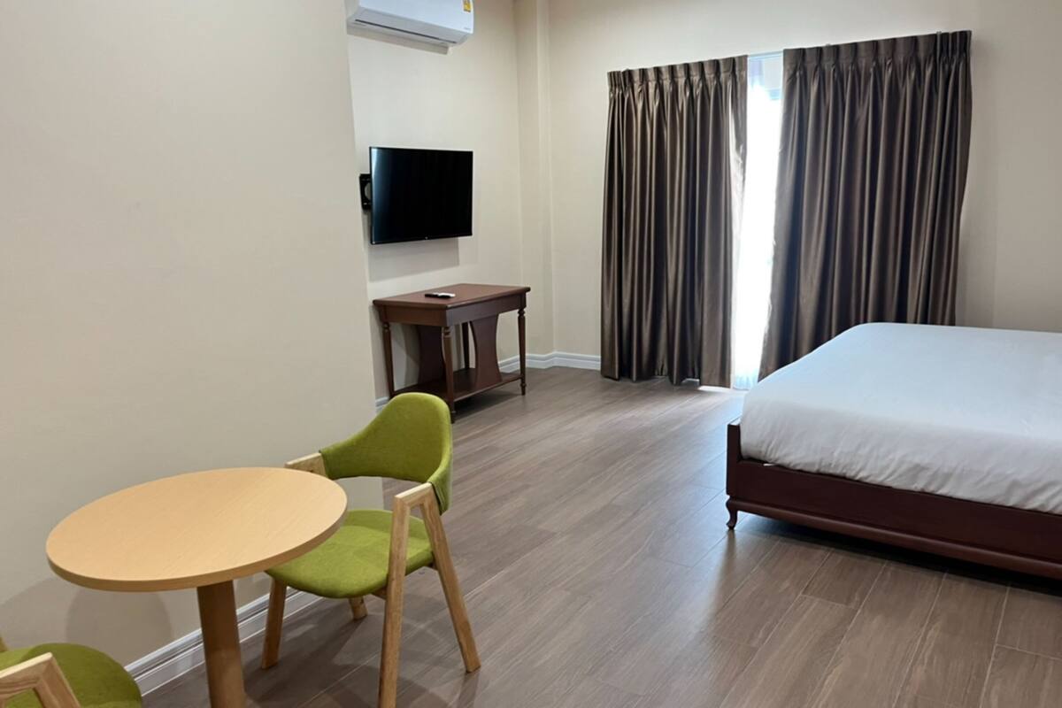 A hotel room with a bed, a desk, a chair, a television, and a window with curtains.