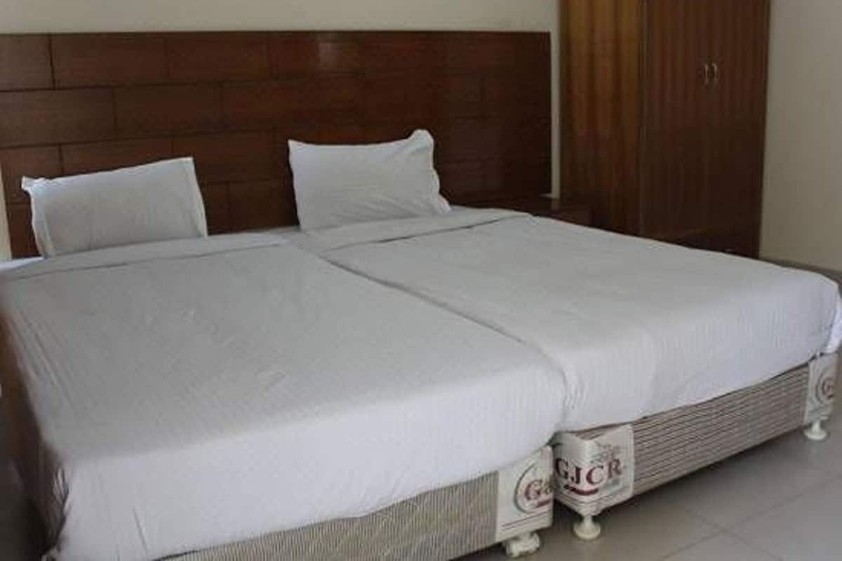 A double bed with a wooden headboard, a wardrobe, and a bedside table with a lamp.