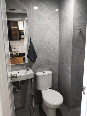 A modern bathroom with a white toilet, a sink, and a mirror. - S&A Property 2 (Tarumajaya)