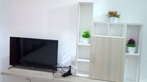 Ein modernes Wohnzimmer mit einem Flachbildfernseher, einer Zieruhr und einem Regal mit Pflanzen.