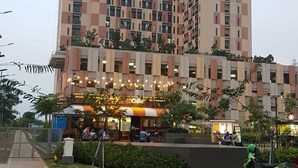 Ein mehrstöckiges Hotel mit Schachbrettmuster-Fassade und einem Café im Erdgeschoss, vor dem eine Straße verläuft.