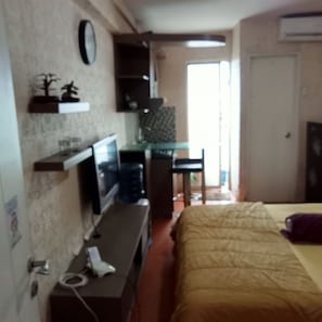 A bedroom with a bed, a desk with a computer, a chair, and a TV. - S&A Property 3 (Jakarta)