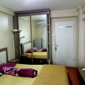 A hotel room with a bed, a wardrobe, a mirror, and a door. - S&A Property 3 (Jakarta)