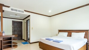 A hotel room with a wooden bed, a desk with a chair, and a bathroom door. - Goodday Kathu (Kathu)
