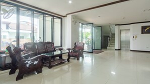 A spacious room with a large glass door leading to a balcony, a wooden coffee table, and several upholstered chairs. - Goodday Kathu (Kathu)