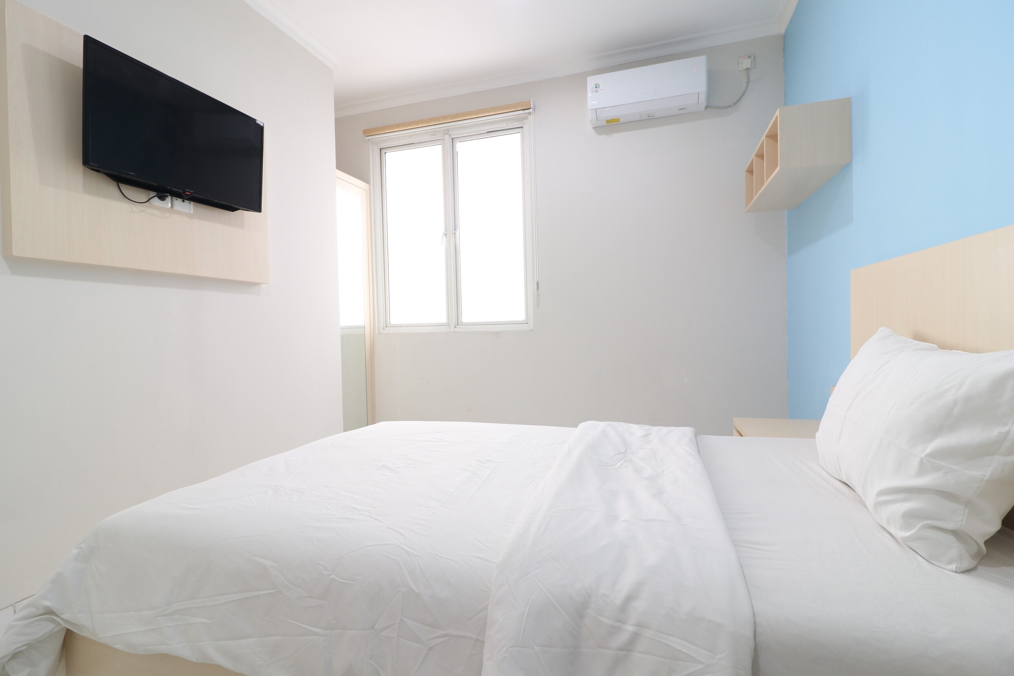 Une chambre d’hôtel équipée d’un lit, d’un téléviseur fixé au mur, d’une fenêtre et d’un appareil de climatisation.
