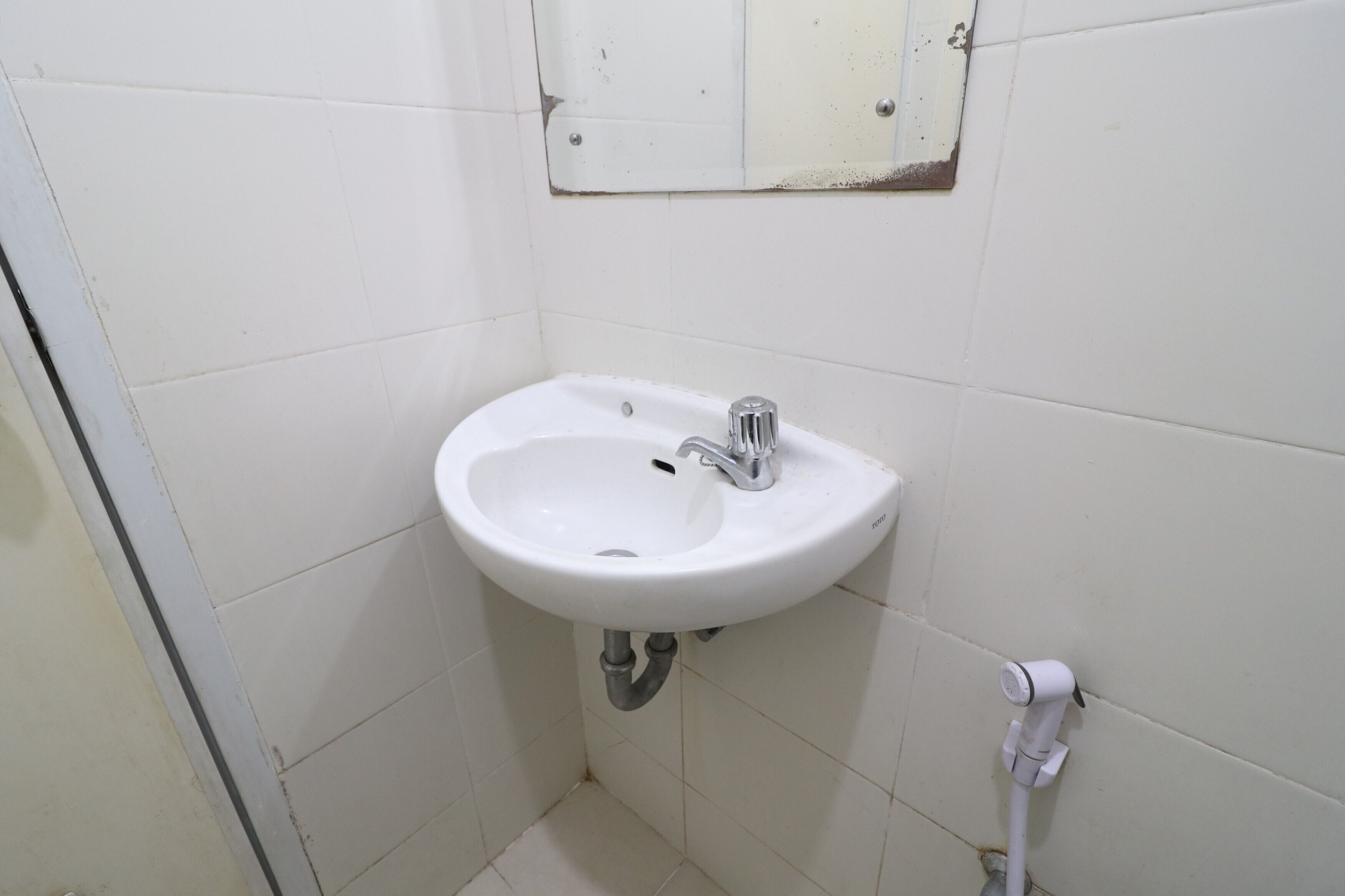 A small, white bathroom with a sink and mirror.
