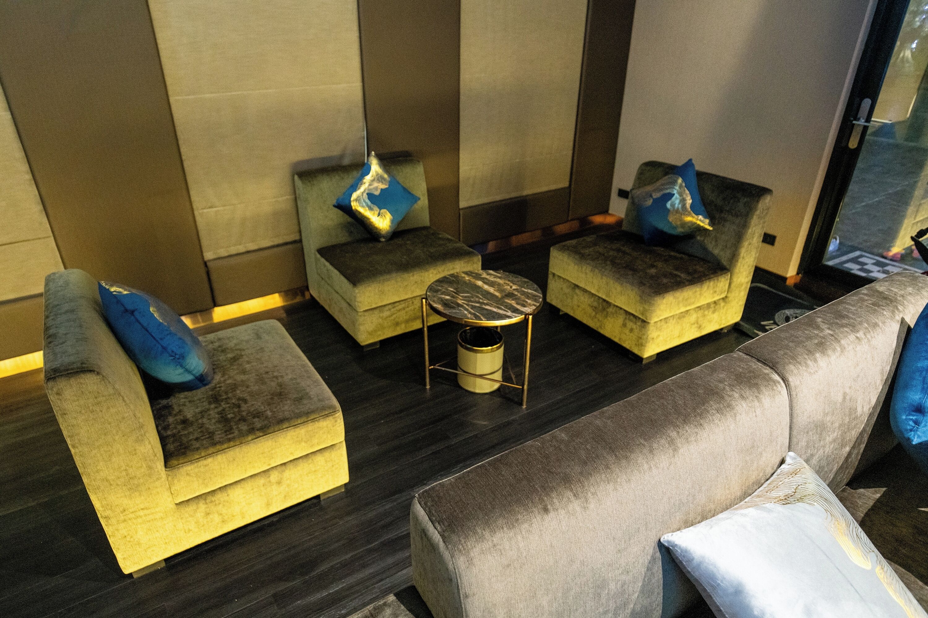 A modern living room with a sofa, two armchairs, and a small round table.