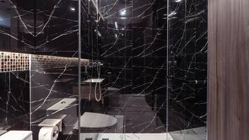 A modern bathroom with a glass shower enclosure, a toilet, and a bidet.