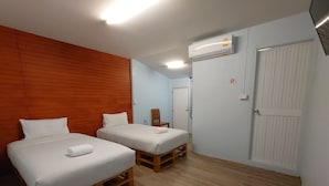 Habitación de hotel con dos camas, piso de madera, una puerta blanca y un equipo de aire acondicionado.