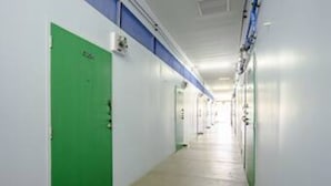 Un pasillo largo y estrecho con puertas a un lado y una estructura azul en el techo.
